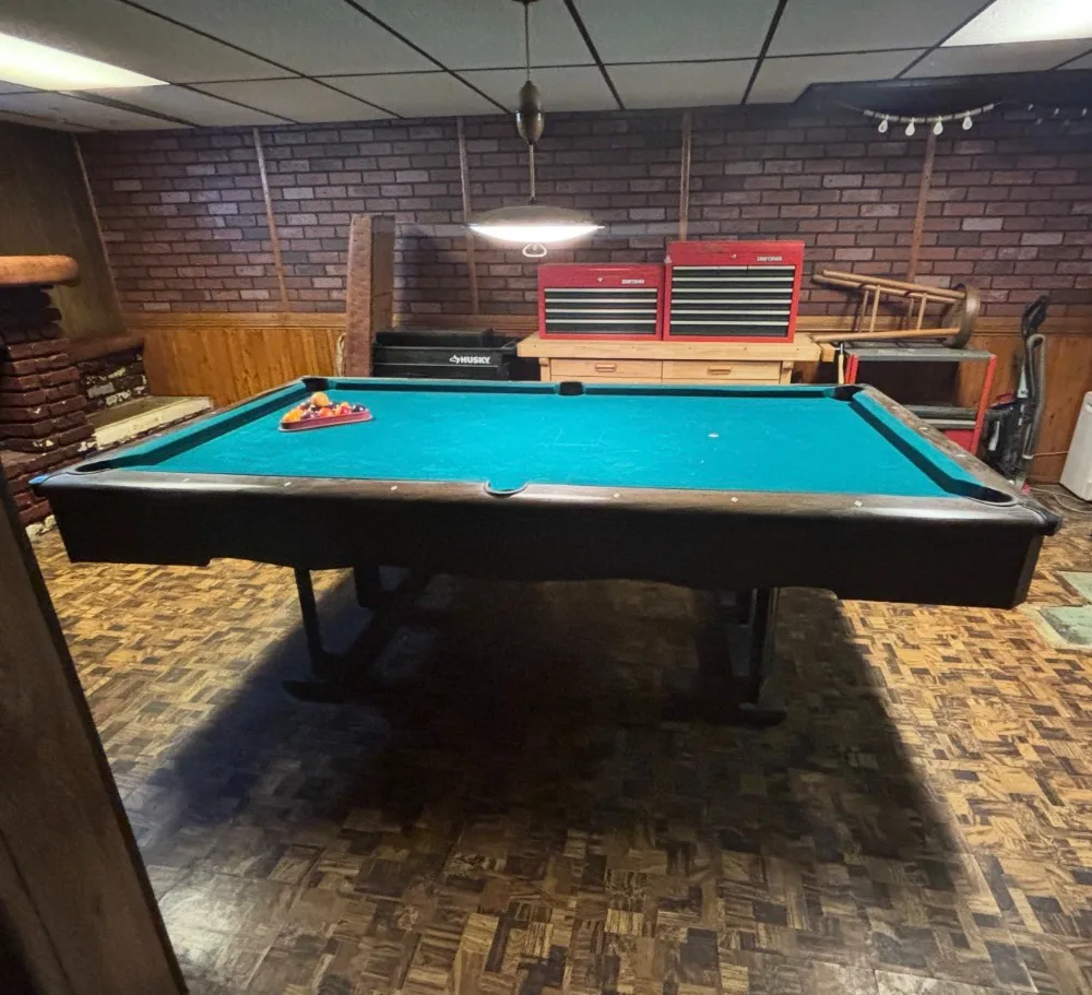 Before: a basement with a pool table, tool chests and clutter against a brick wall